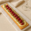 Rectangular artisan flatbread topped with cream cheese, grapes, herbs, highlighting rustic bakery’s olive oil